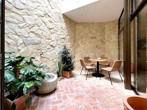 科尔多瓦Arcos de Medina - Apartamentos premium的一间设有石墙和桌椅的房间