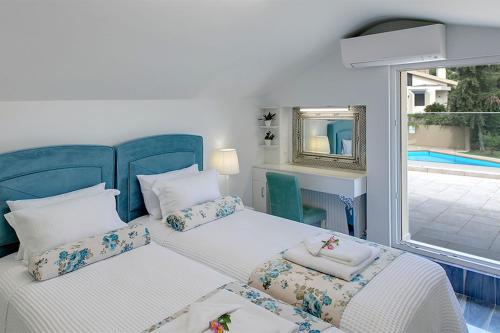 撒尼海滩Azalea Villa Sani, Sani Luxury Villas Collection的一间卧室设有两张床,享有游泳池的景色