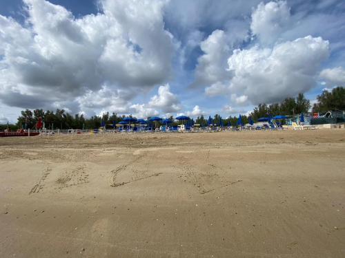 玛里纳蒂蒙内罗Maronda Camping的阴天带椅子和遮阳伞的海滩