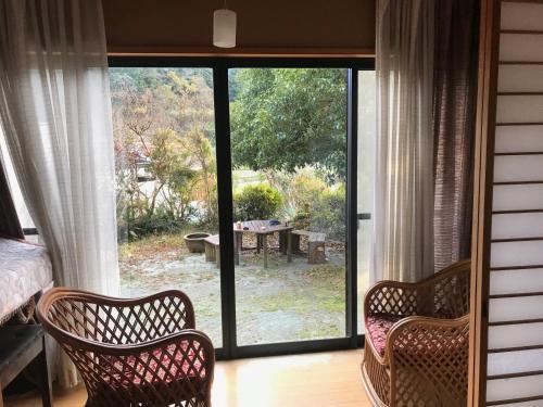 筑紫野市Yamabitoan - Vacation STAY 04295v的一间设有两把椅子和滑动玻璃门的房间