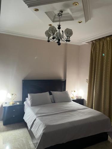 开罗Rehab City VIP Full Serviced Apartment الرحاب Guest satisfaction guaranteed的一间卧室配有一张大床和一个吊灯。