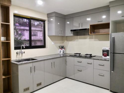 加德满都YULOKO GUEST HOUSE的厨房配有白色橱柜和不锈钢冰箱