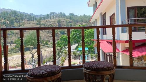 阿尔莫拉Shivalik River Retreat的阳台设有2张凳子,享有山景