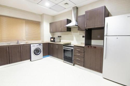 迪拜Better Living Apartment的厨房配有木制橱柜和白色冰箱。