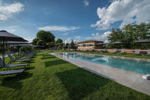埃尔萨谷口村帕拉佐圣洛伦索Spa酒店的一个带草坪椅和遮阳伞的游泳池