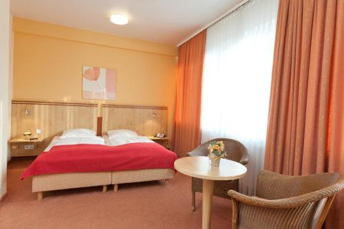 汉堡帝国酒店的一间卧室配有红色的床和一张桌子