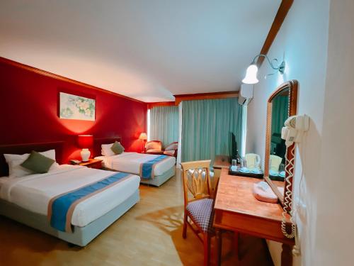 乌汶Ubonburi Hotel的酒店客房配有两张床和一张书桌