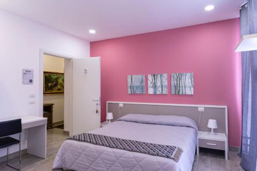 诺瓦拉Ventitrémarzo Guest House的卧室设有粉红色的墙壁、一张床和一张书桌