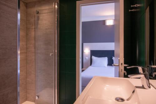巴黎Hôtel Baldi by Magna Arbor的一间带水槽的浴室和一间带一张床的卧室