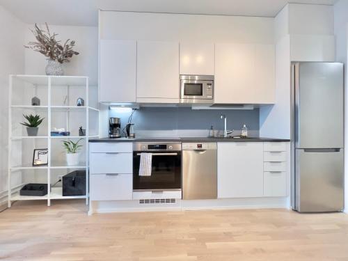 赫尔辛基Stunning Central Apartment Helsinki的厨房配有白色橱柜和不锈钢冰箱