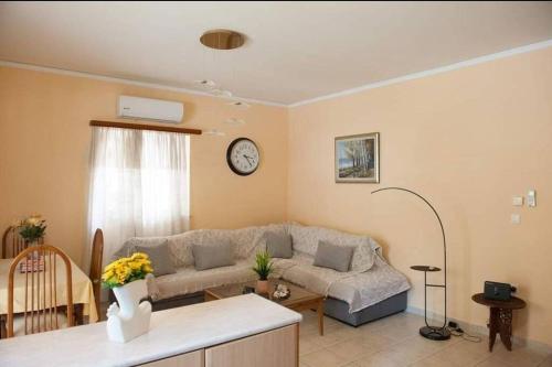 普雷韦扎Meropi Apartment的客厅配有沙发和墙上的时钟