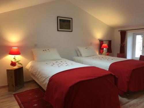 BonnesLa biche的一间卧室配有两张带红色床单和灯具的床。