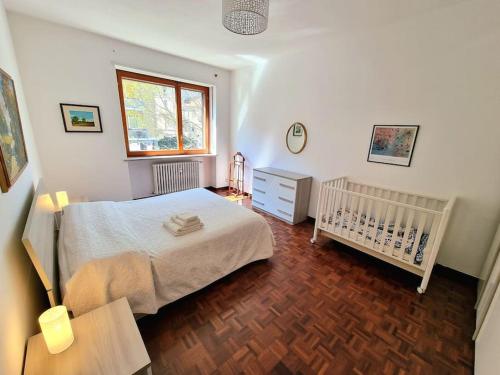 伊夫雷亚Casa del tennis的一间卧室配有一张床、一张婴儿床和一扇窗户。