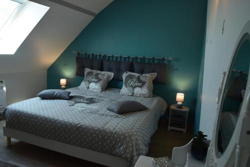Saint-Père-sur-Loireô temps de l'escapade的一间卧室配有带枕头的床铺和蓝色的墙壁
