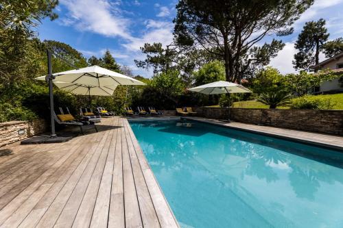 比达尔SERENITY - KEYWEEK Bidart swimming pool villa的木制甲板旁的游泳池配有遮阳伞和椅子
