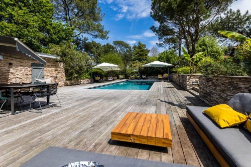比达尔SERENITY - KEYWEEK Bidart swimming pool villa的后院设有游泳池和带桌子的木甲板