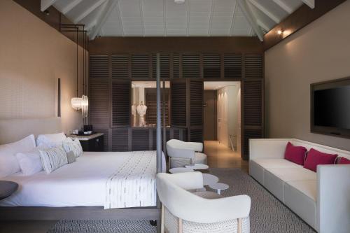 古斯塔维亚Le Barthélemy Hotel & Spa的一间卧室配有一张床、一张沙发和一台电视。