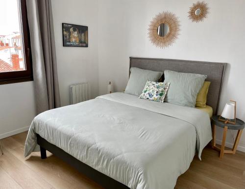 拉罗谢尔Appartement Saint-Nicolas的卧室配有一张带镜子的白色大床