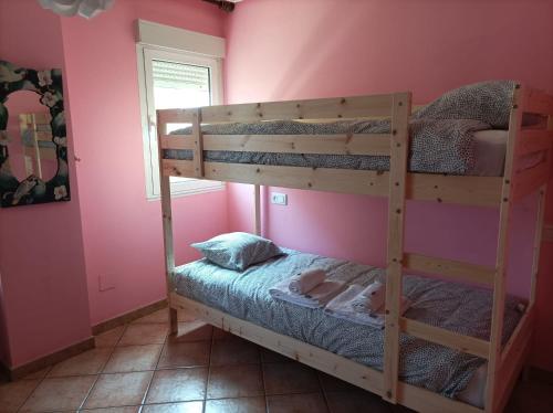 NavecesLa Cariñosa的卧室配有两张双层床,位于带粉红色墙壁的房间内