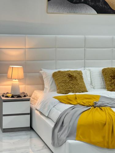 塞拉莱Sky ittin سما إتين的白色的床,配有黄色和白色床单和灯
