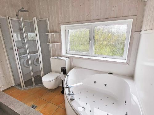 格洛米茨Three-Bedroom Holiday home in Grömitz 13的带浴缸、卫生间和窗户的浴室