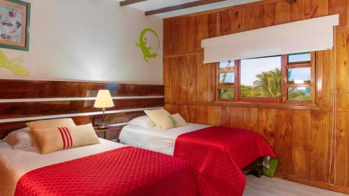 比亚米尔港木屋酒店的一间卧室设有两张带红色床单的床和窗户。