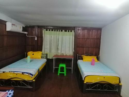 湄宏颂Lungmin homestay的一间设有两张床、一张桌子和一把椅子的房间