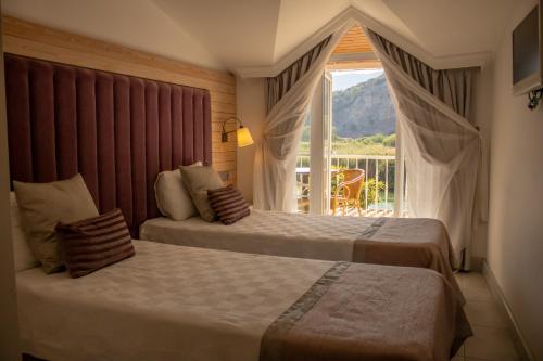 穆拉Aktaş Butik Hotel的带阳台的酒店客房内的两张床