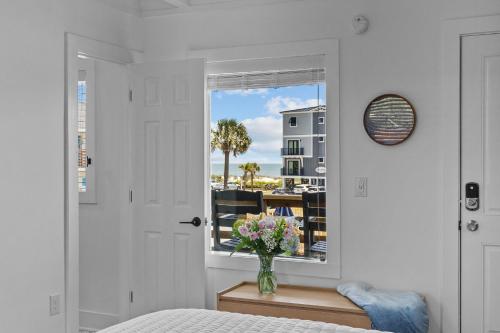 橡树岛The Beach House at Oak Island by Carolina Resorts的卧室设有窗户,桌子上放着花瓶
