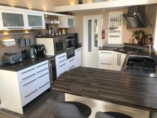 拉尔Hot Tub Accommodation North Wales Lodge的厨房配有白色橱柜和木制台面