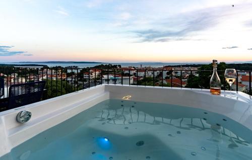 PalitPanorama Suite Dora with Jacuzzi的阳台上的热水浴缸和一瓶葡萄酒