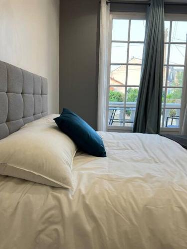 塞夫朗Appartement Élégant proche RER/ CDG / Parc des Expos的一张带蓝色枕头的白色床和窗户