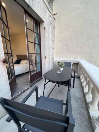 塞夫朗Appartement Élégant proche RER/ CDG / Parc des Expos的阳台配有桌椅和1张床。