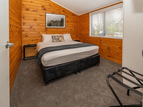 罗托鲁瓦Tasman Holiday Parks - Rotorua的木制客房内的一间卧室,配有一张床