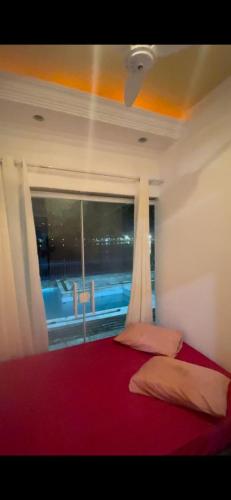 圣维森特岛Hostel Parque Prainha的一间卧室设有大窗户和一张红色的床