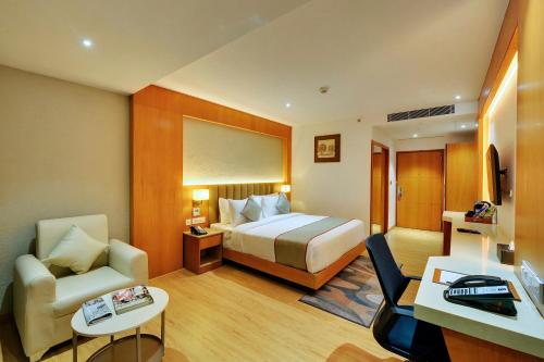 班加罗尔Clarion Hotel Bangalore的配有一张床和一把椅子的酒店客房
