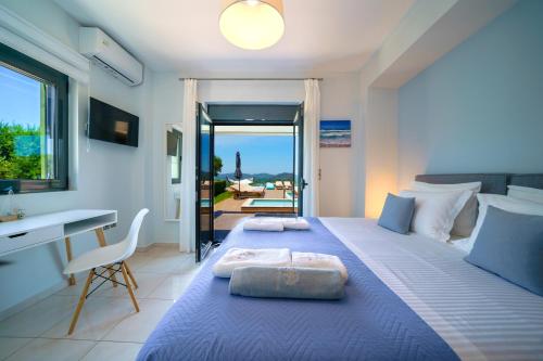 PerivóliaMythic Olive villa - Heated Pool - Amazing view的一间卧室配有一张蓝色的床、一张桌子和一个窗户。