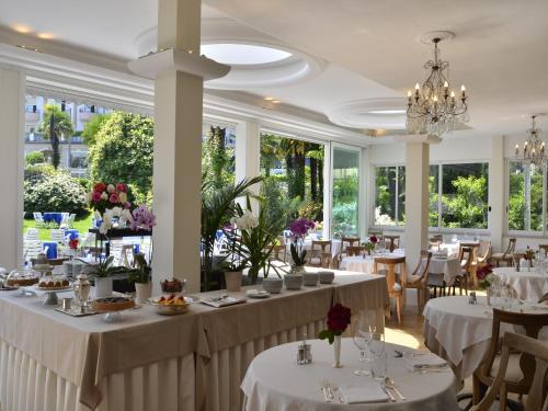 斯特雷萨皇家酒店的一间设有白色桌椅和窗户的用餐室