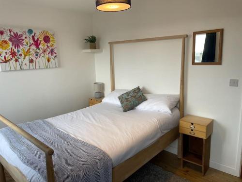 特鲁罗Stunning, Modern and Spacious House - Truro的小卧室配有一张带床头柜和照片的床