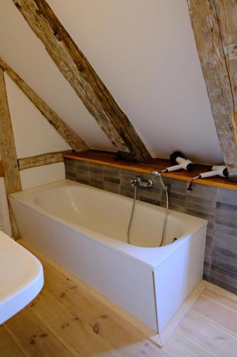 DassowGutshaus FeWo Brook的浴室设有白色浴缸,拥有木制天花板