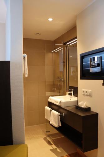 安德纳赫EINSTEIN Hotel am Römerpark的一间带水槽的浴室和墙上的电视