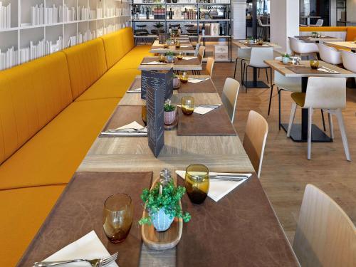 穆耶龙·勒卡普蒂夫ibis Styles La Roche-sur-Yon的餐厅里一排黄色墙壁的桌子
