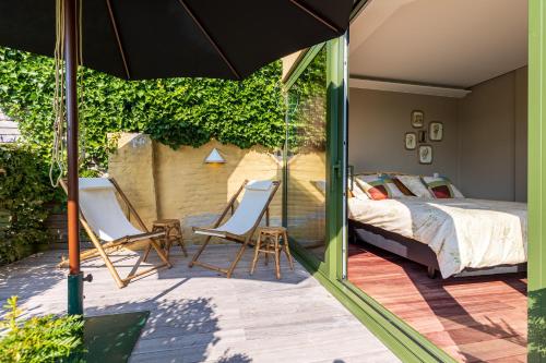 代因泽Villa Francine的一间卧室配有一张床、两把椅子和一把遮阳伞