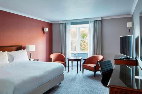杜伦Delta Hotels by Marriott Durham Royal County的酒店客房带一张床、一张桌子和椅子
