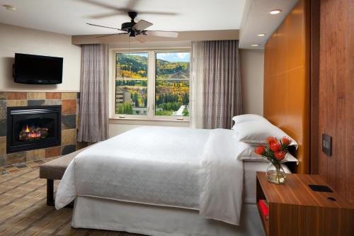 埃文Sheraton Mountain Vista Villas, Avon / Vail Valley的一间卧室设有一张大床和一个壁炉