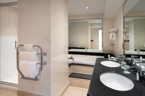 北安普敦Delta Hotels by Marriott Northampton的浴室配有两个盥洗盆和浴缸。