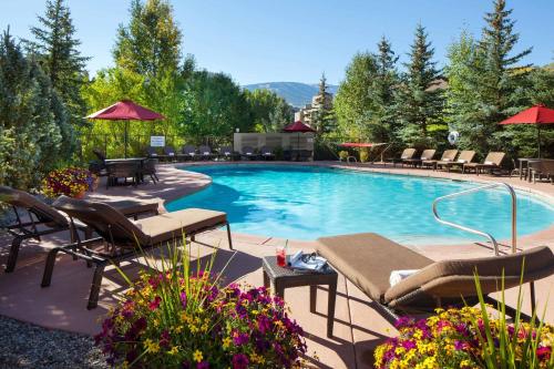 埃文Sheraton Mountain Vista Villas, Avon / Vail Valley的一个带椅子和遮阳伞的游泳池