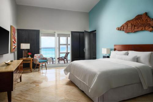 坎昆坎昆威斯汀Spa度假酒店的卧室配有一张白色大床、一张桌子和椅子