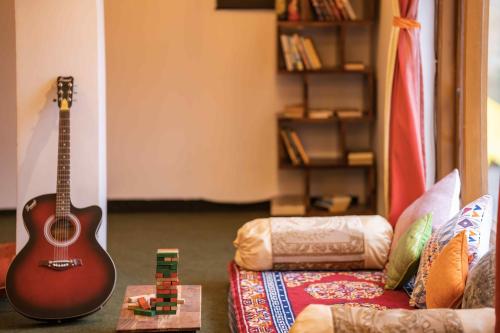 加沙左思特尔斯皮蒂旅舍的坐在沙发旁边的地板上的吉他