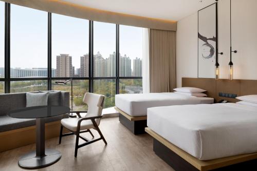 西安西安浐灞万枫酒店的酒店客房带两张床、一张桌子和一张沙发